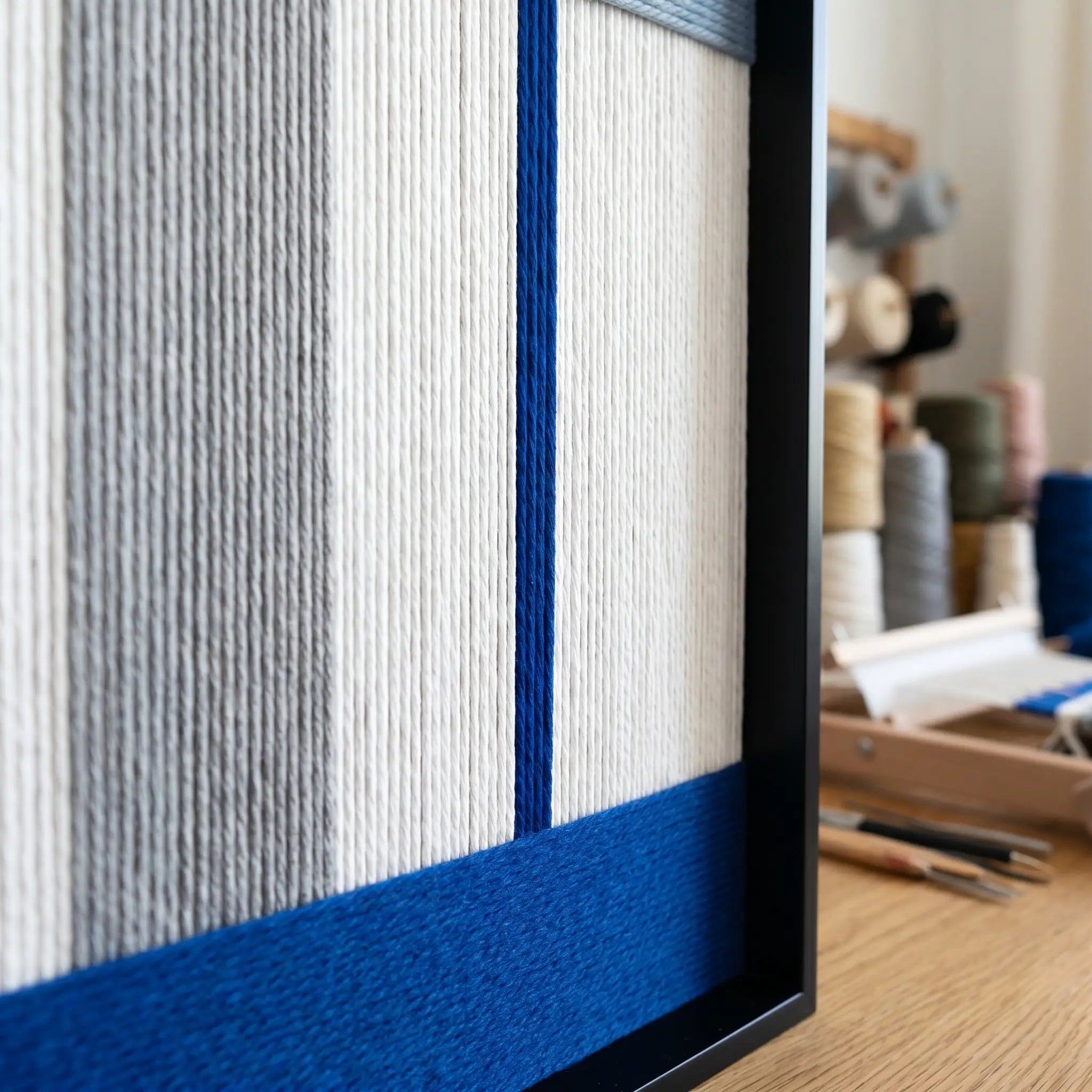 Detailed view of the vibrant blue wool section and black metal frame of the Absolute Zero textured fiber wall art.
