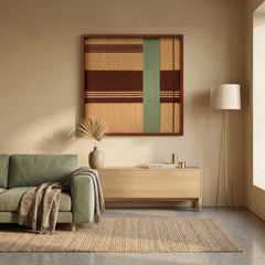 Framed geometric textile wall art displayed above a light wood console table next to a sage green sofa in a warm, minimalist living room.