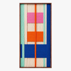 Full product shot of the geometric hand-woven wool wall art in a sleek metal frame, highlighting its vibrant blocks of blue, pink, and orange yarn.
