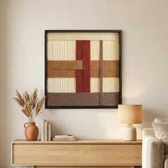 Framed fiber wall art creating a warm atmosphere in a lounge area, styled above a light wood console table with a soft table lamp.