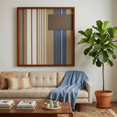 Coastal Diary square hand-woven wall art displayed in a warm living room above a beige sofa draped with a vibrant blue throw blanket next to a large fiddle leaf fig plant.