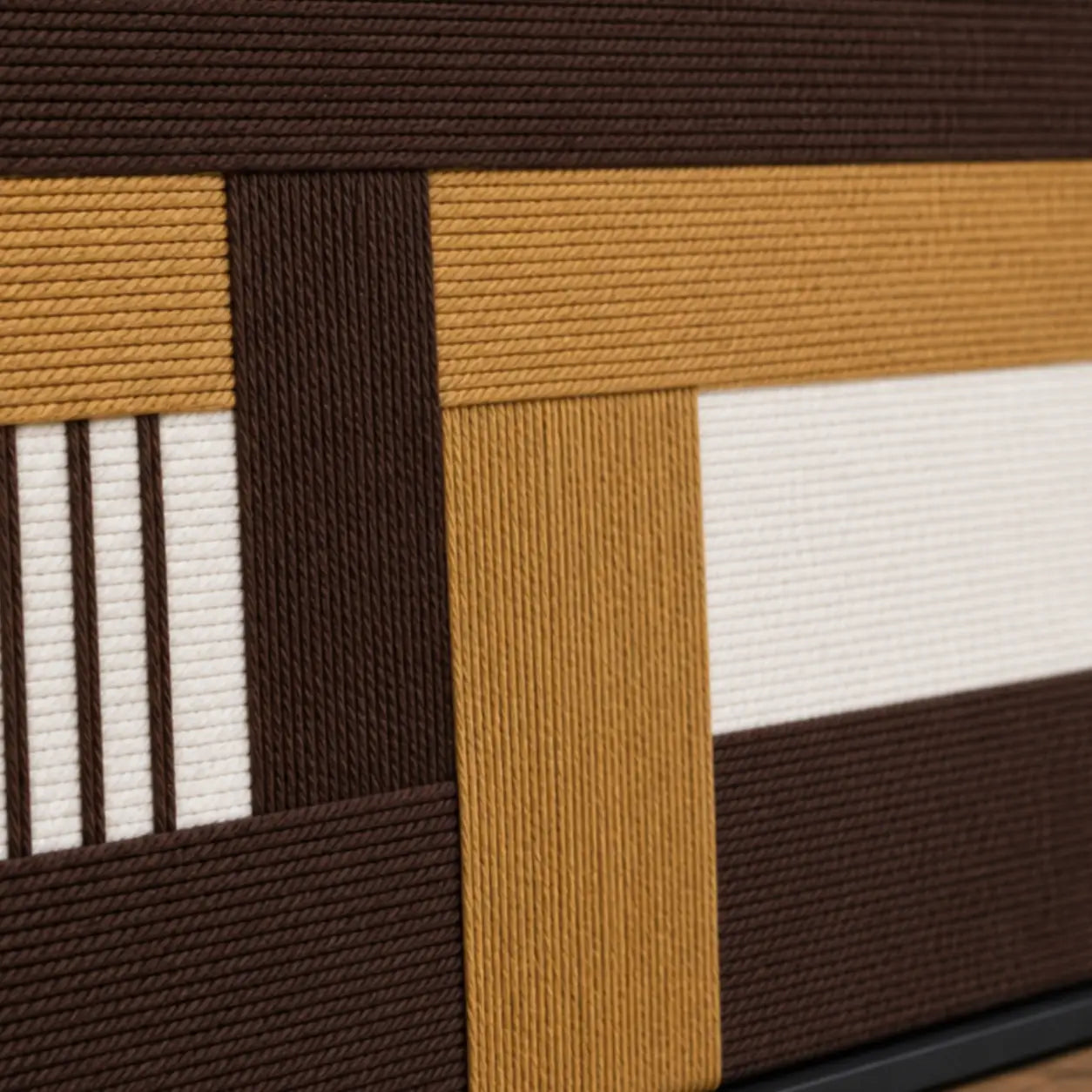 Detailed macro close-up of the Cocoa Loom hand-woven wool tapestry highlighting the thick brown, beige, and white intersecting yarn textures.
