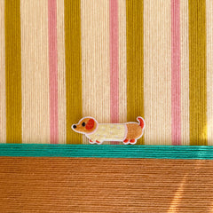 Macro shot of the hand-woven wool texture showing the raised coral and olive stripes and the embroidered dog character detail.