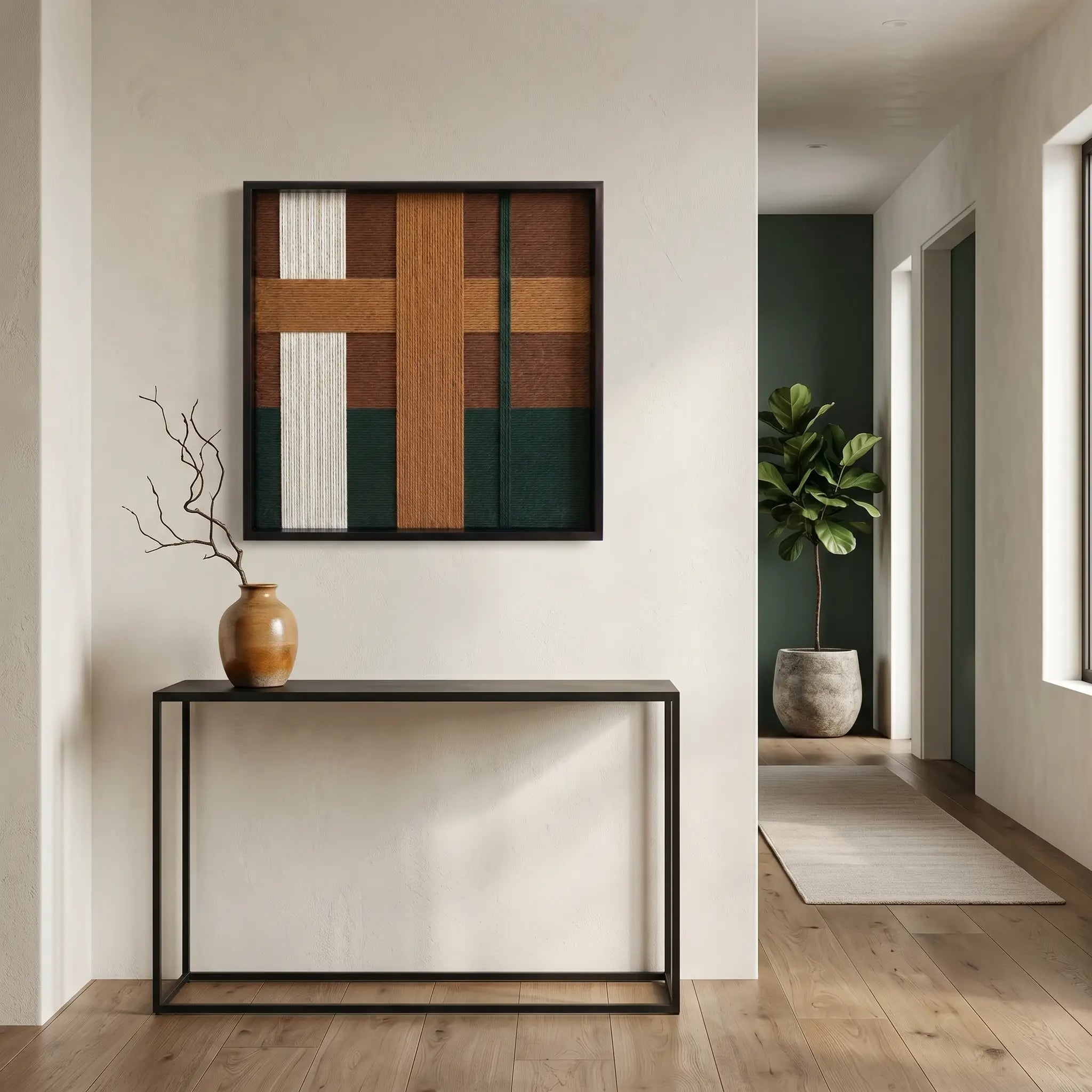 Textured wool wall art styled in a minimalist entryway above a slim black metal console table with a ceramic vase.