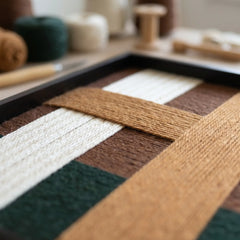 Detailed macro shot of the Emerald Fables fiber art in a studio, highlighting the intricate hand-wrapped yarn and structural multi-directional layering.