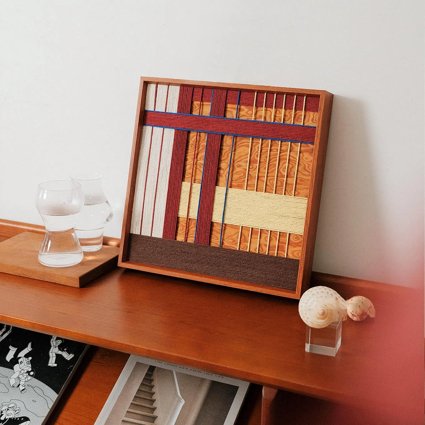 Angled view of the hand-woven art piece displayed on a wooden sideboard with glassware, showcasing its suitability for dining room decor.