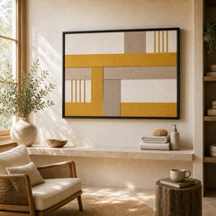 Framed hand-woven wool tapestry styled in a sunlit lounge nook, positioned above a stone shelf next to a wooden armchair.