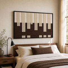 A beautiful hand-woven wool tapestry displayed beautifully above a styled bed with brown accents in a warm bedroom.