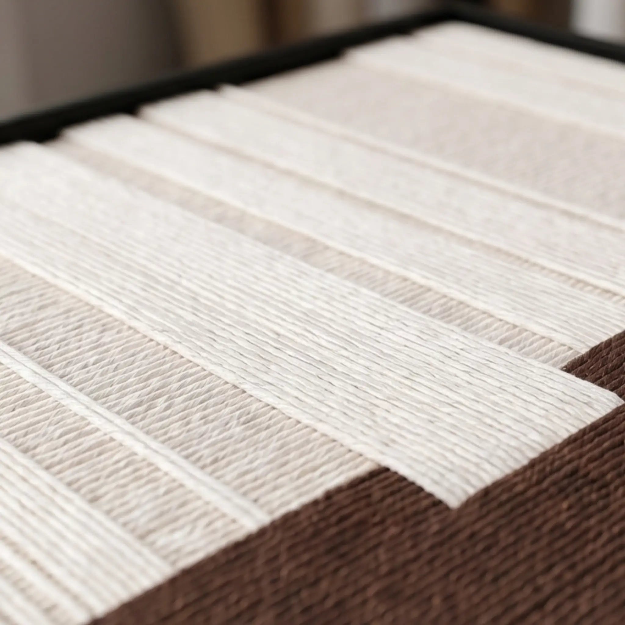 Angled macro close-up of the Ivory Rhythm hand-woven wool tapestry highlighting the thick, raised cream vertical yarn over a brown textured base.
