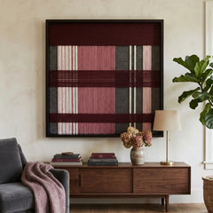 Large square Merlot Veil hand-woven wall art hanging elegantly above a mid-century wooden credenza next to a grey sofa draped with a mauve throw blanket.