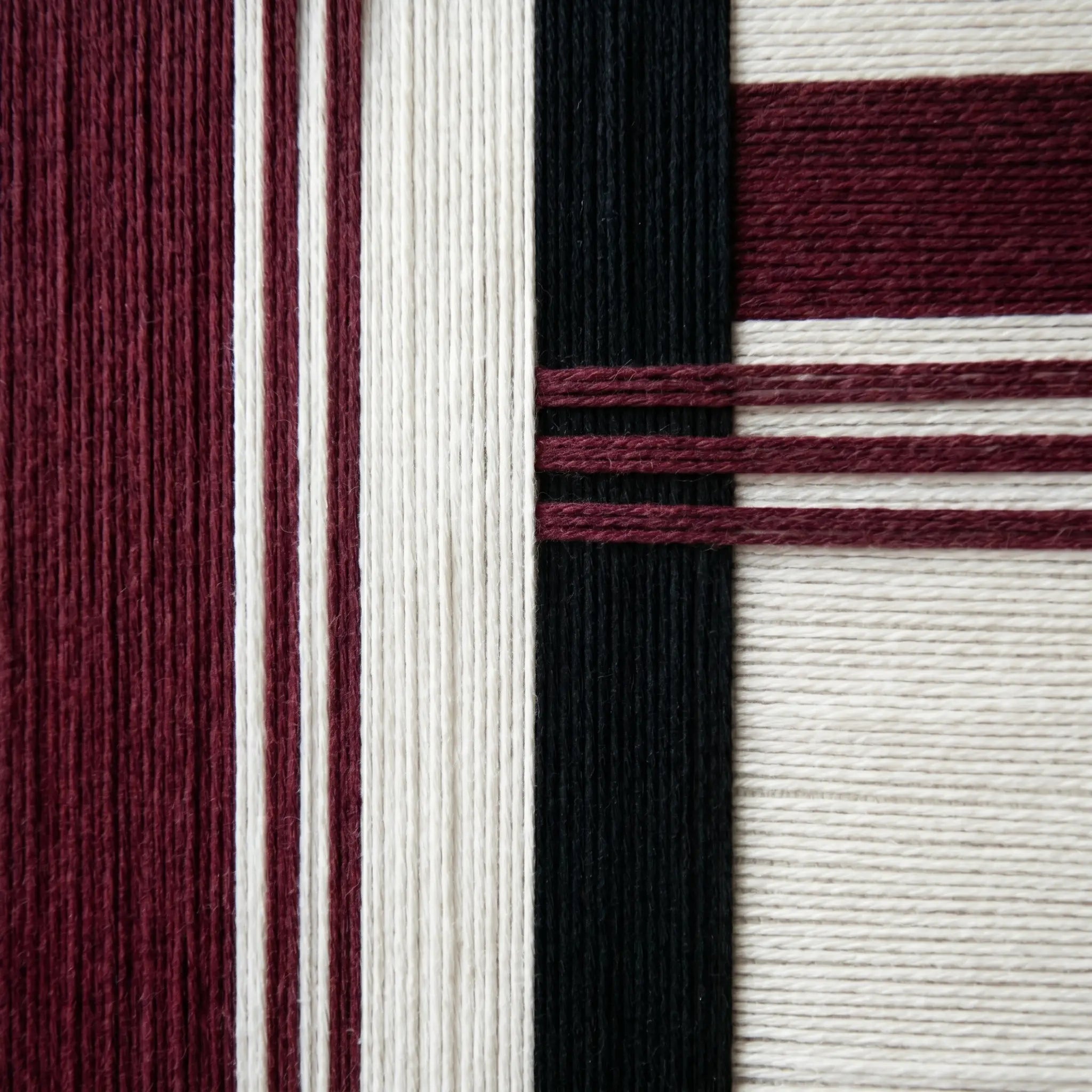 Detailed macro shot of the Midnight Opera wool tapestry highlighting the rich burgundy and black hand-wrapped yarn textures.