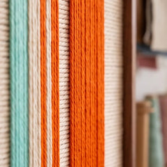 Close-up of the hand-woven wool texture in the Midtown Rhythm wall art, showcasing detailed vertical fiber lines and vibrant orange and teal colors.