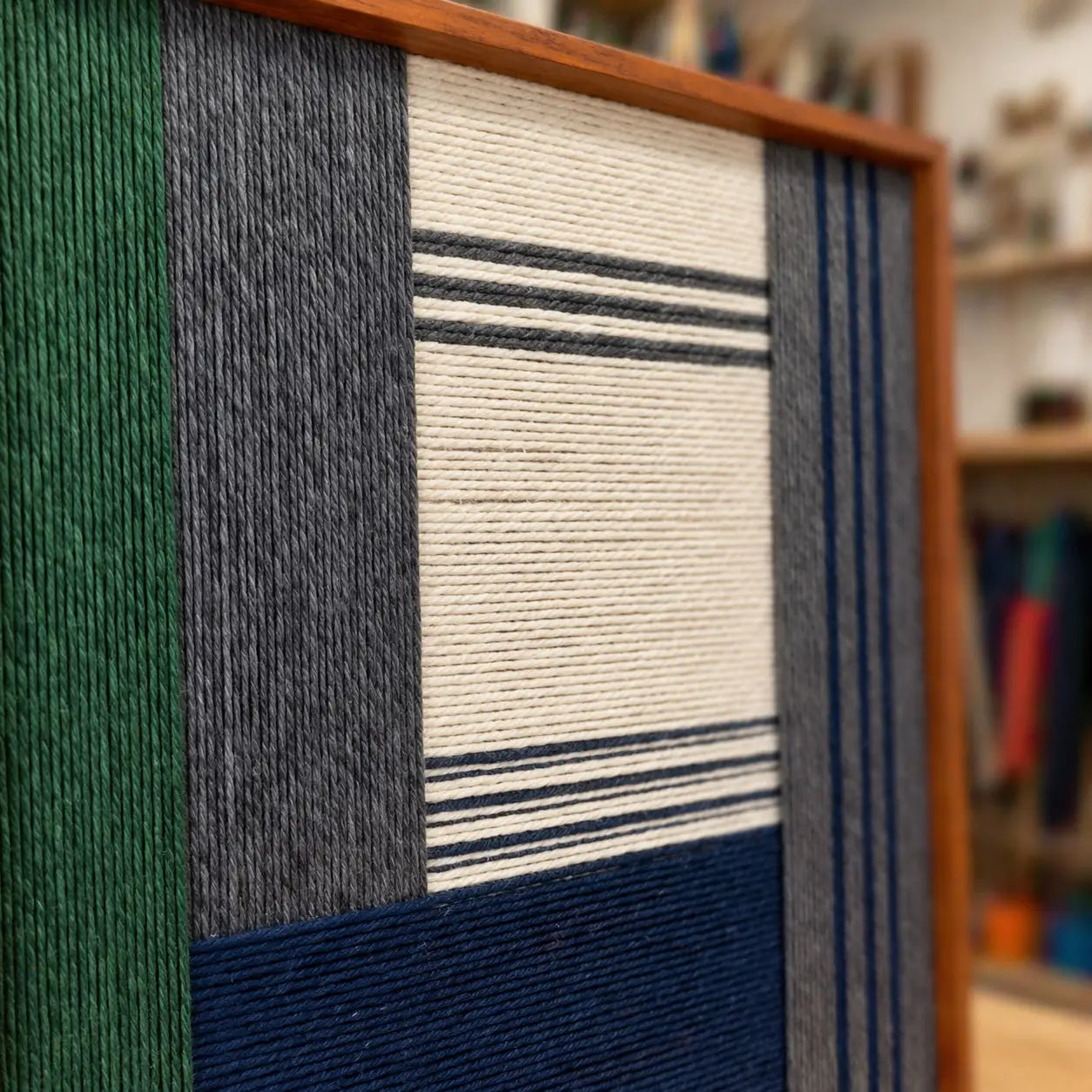 An angled view of the framed wool art highlighting the high-value texture of the hand-wrapped yarn and structural geometric patterns.