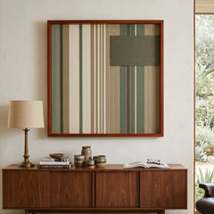 Earth-toned Olive Solitude framed wall art styled elegantly above a warm dark wood sideboard adorned with a modern lamp and small ceramics.