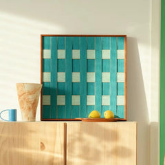 Square textured wool wall decor placed above a light wood cabinet, highlighting the vibrant coastal teal tones and organic materials.