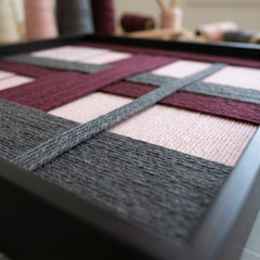 Angled perspective of the textured fiber wall art highlighting the interlocking hand-wrapped yarn and structural layering technique.