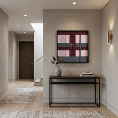 Square hand-woven wool tapestry styled above a slim black metal console table in a bright, modern entryway.
