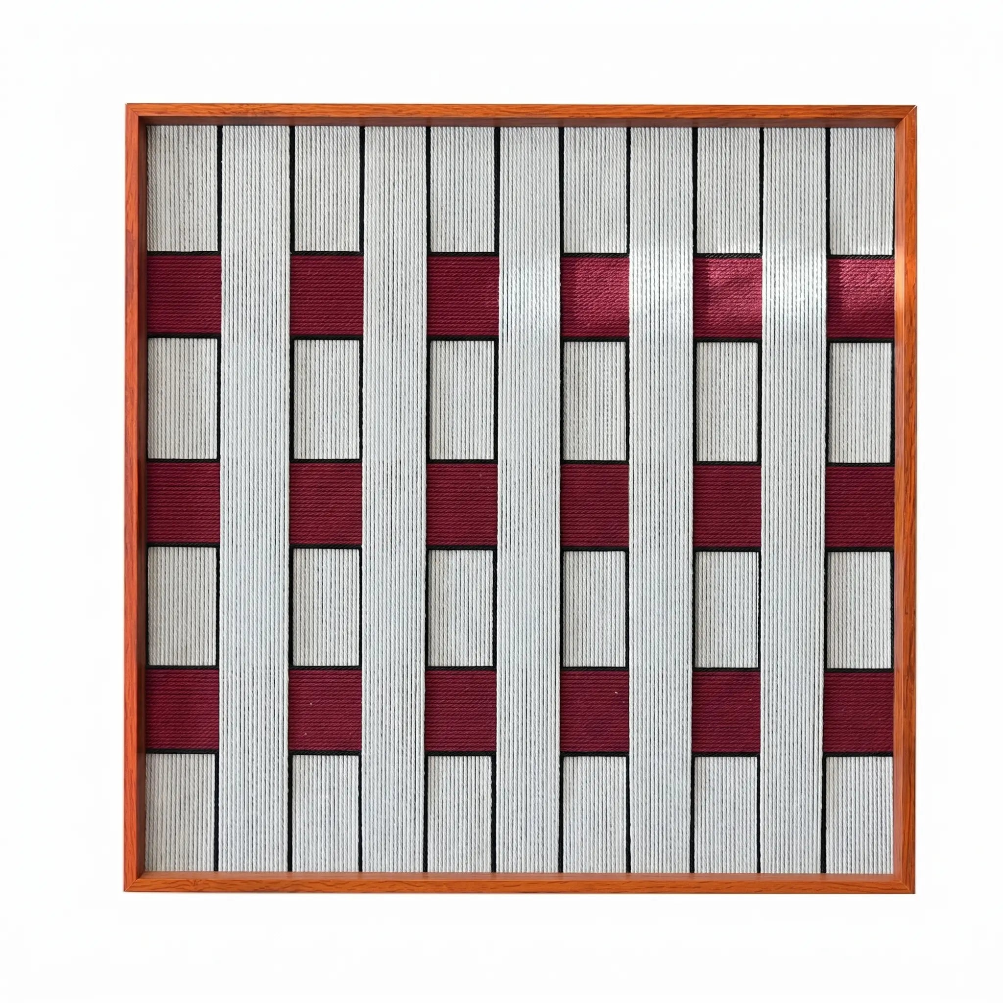 Frontal studio shot of the Ruby Lattice hand-woven wool wall art featuring a grey and burgundy checkerboard pattern in a wood frame against a clean white background.