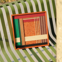 Saint Christmas yarn woven art resting on a green garden bench outdoors, showcasing durable wool texture and festive color palette
