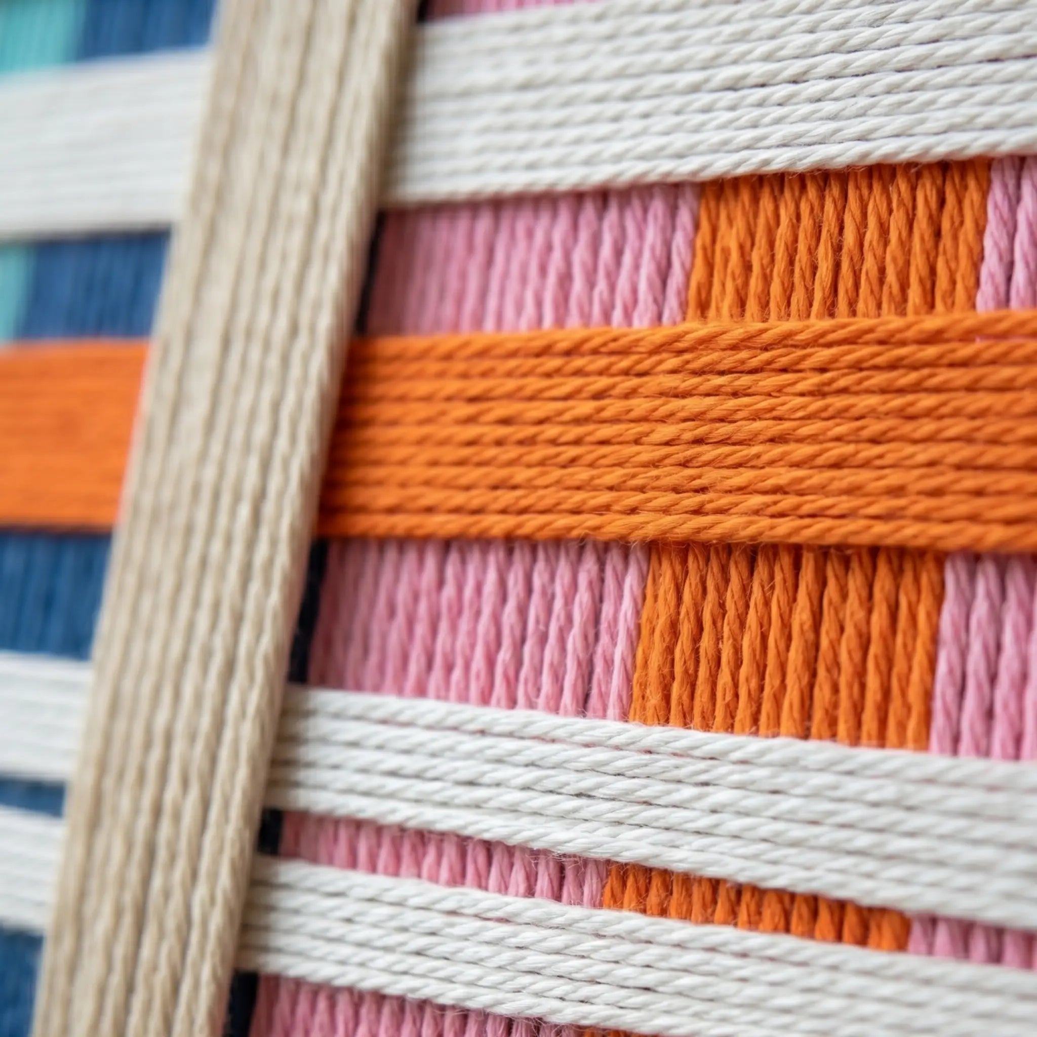 Framed colorful hand-woven wool wall art styled in a serene bedroom as a striking focal point above a warm wood bed frame.