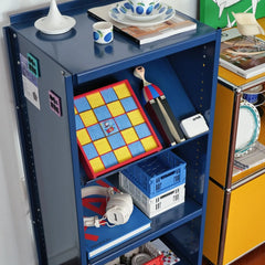 The Snoopy Space Odyssey wool art displayed on a blue metal shelving unit, adding a playful pop of color to a modern room setup.