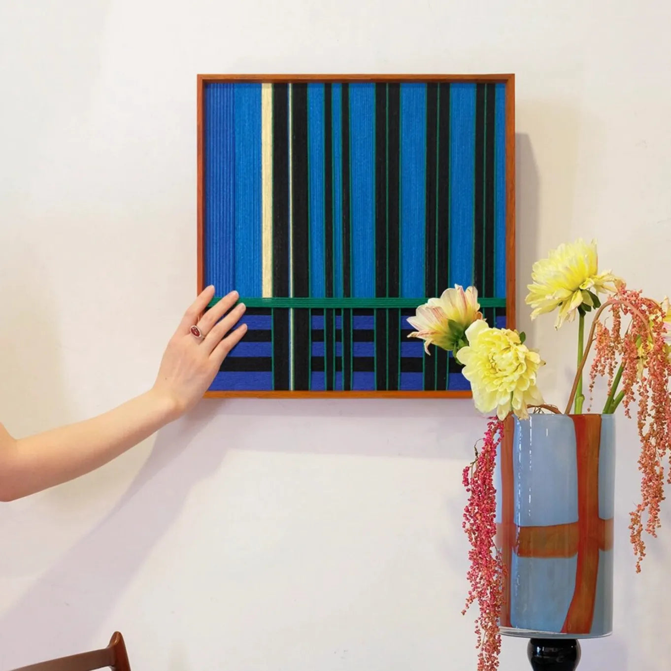 Summer Night’s Serenity wall art being installed on the wall, highlighting easy hanging and its bold blue-green striped design