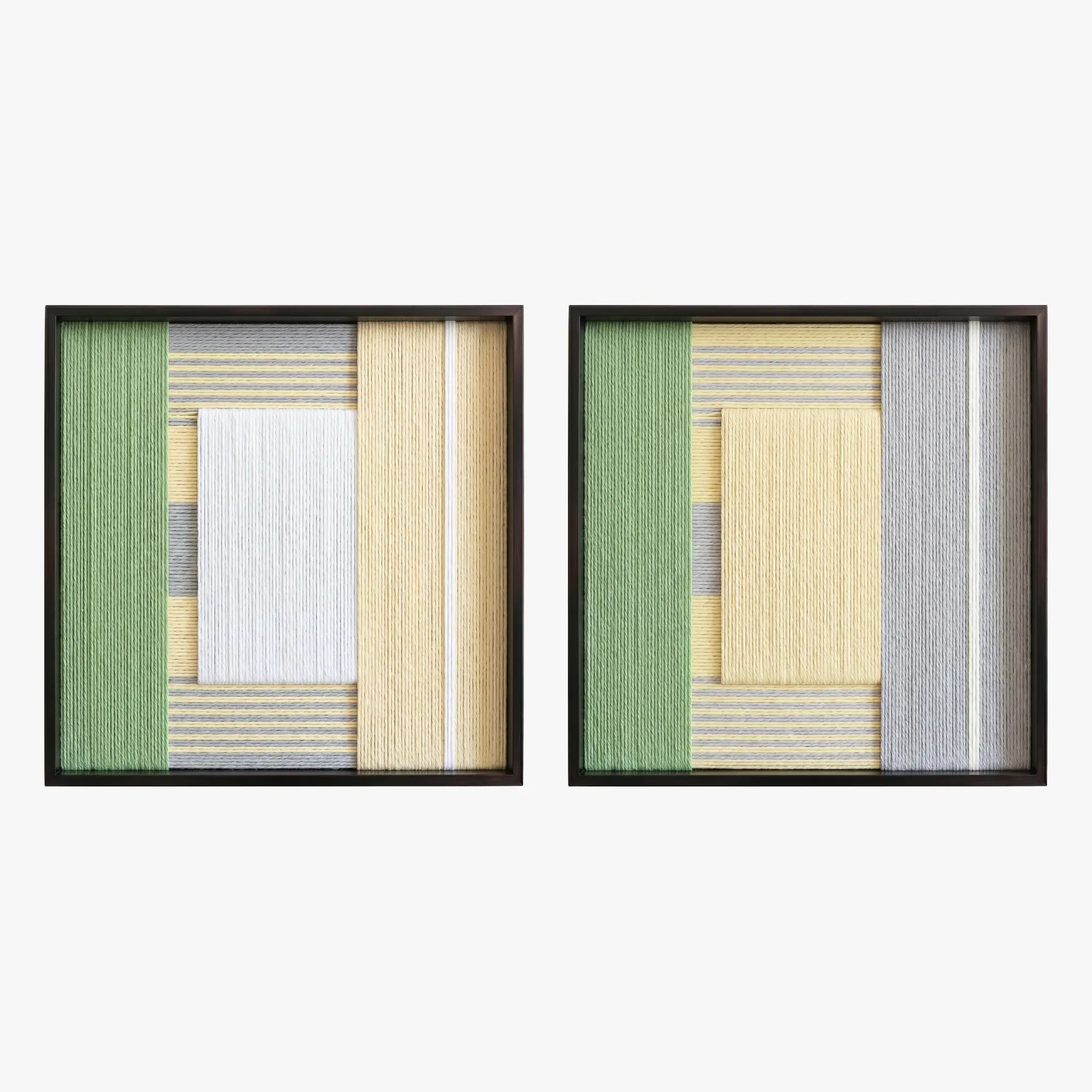 Frontal studio shot of the Sun-Baked textile art pair, showcasing two matching square hand-woven wall art pieces with yellow, white, and green geometric designs in black frames.