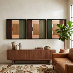 A triptych of Sylvan Glow hand-woven textile art displayed above a cozy brown leather sofa in a bright, modern living room setting.