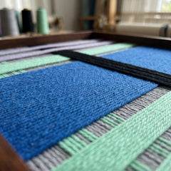 Extreme close-up of the Winter Aurora tapestry showcasing the dense, high-texture cobalt blue and black hand-wrapped wool yarn within a wooden frame.