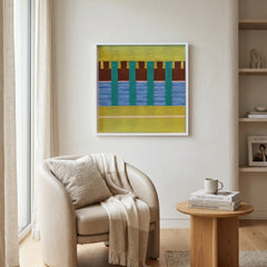 Framed vibrant green and blue textile wall art styled in a cozy reading corner above a cream armchair and small wooden side table.