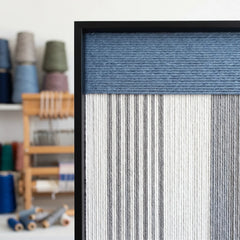Close-up of the hand-woven wool texture and black frame corner, highlighting the high-quality blue and white yarn craftsmanship.