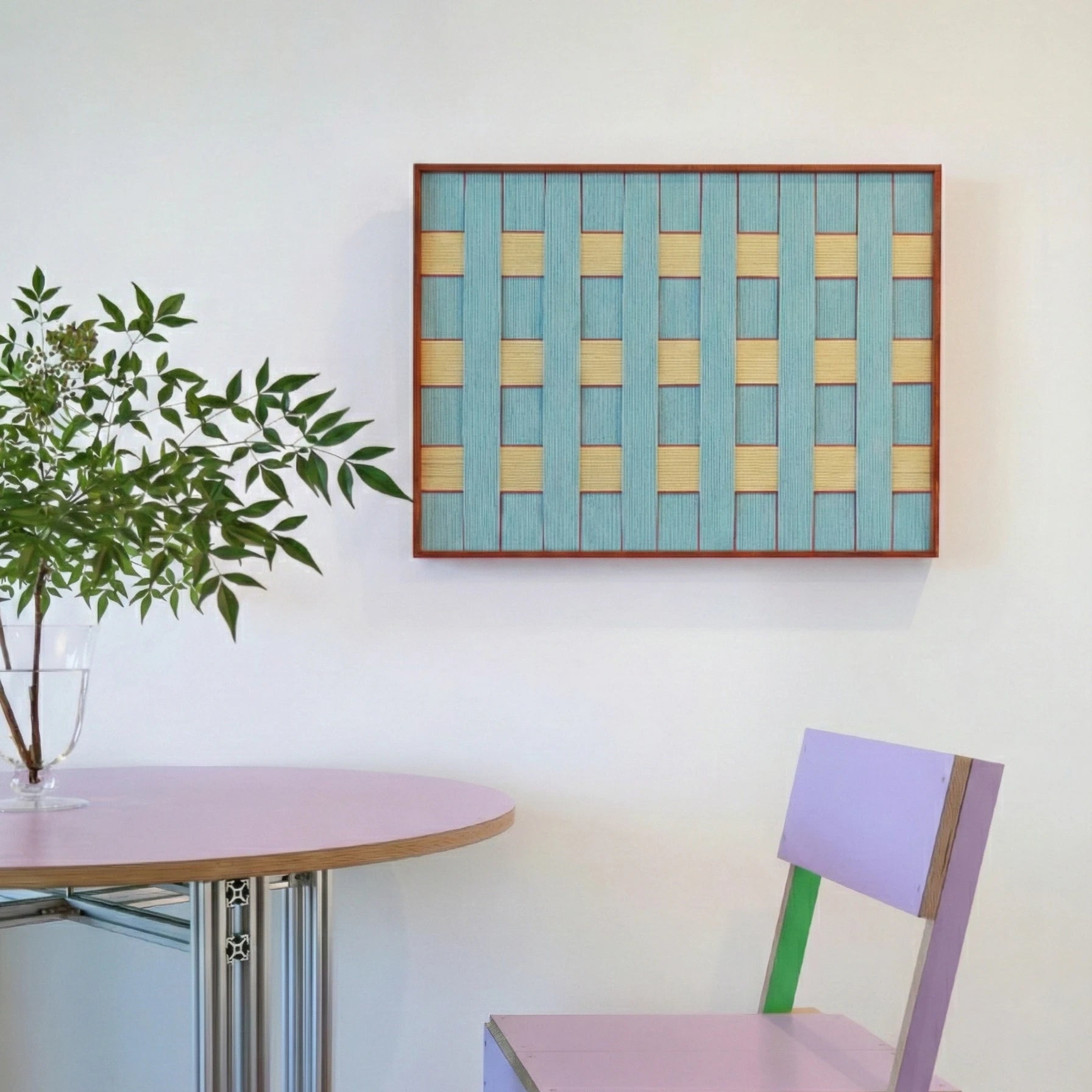 Modern hand-woven wool wall hanging styled in a bright dining area next to a minimalist round table and purple chair.