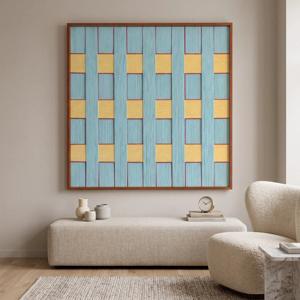 The Afternoon Window hand-woven wool tapestry provides a striking geometric focal point above a modern sofa in a bright room.