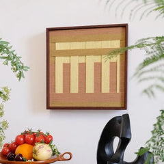Autumn Mountain yarn wall art styled on a desk beside a fruit bowl and black sculpture, emphasizing its textured wool weave and autumnal color palette.
