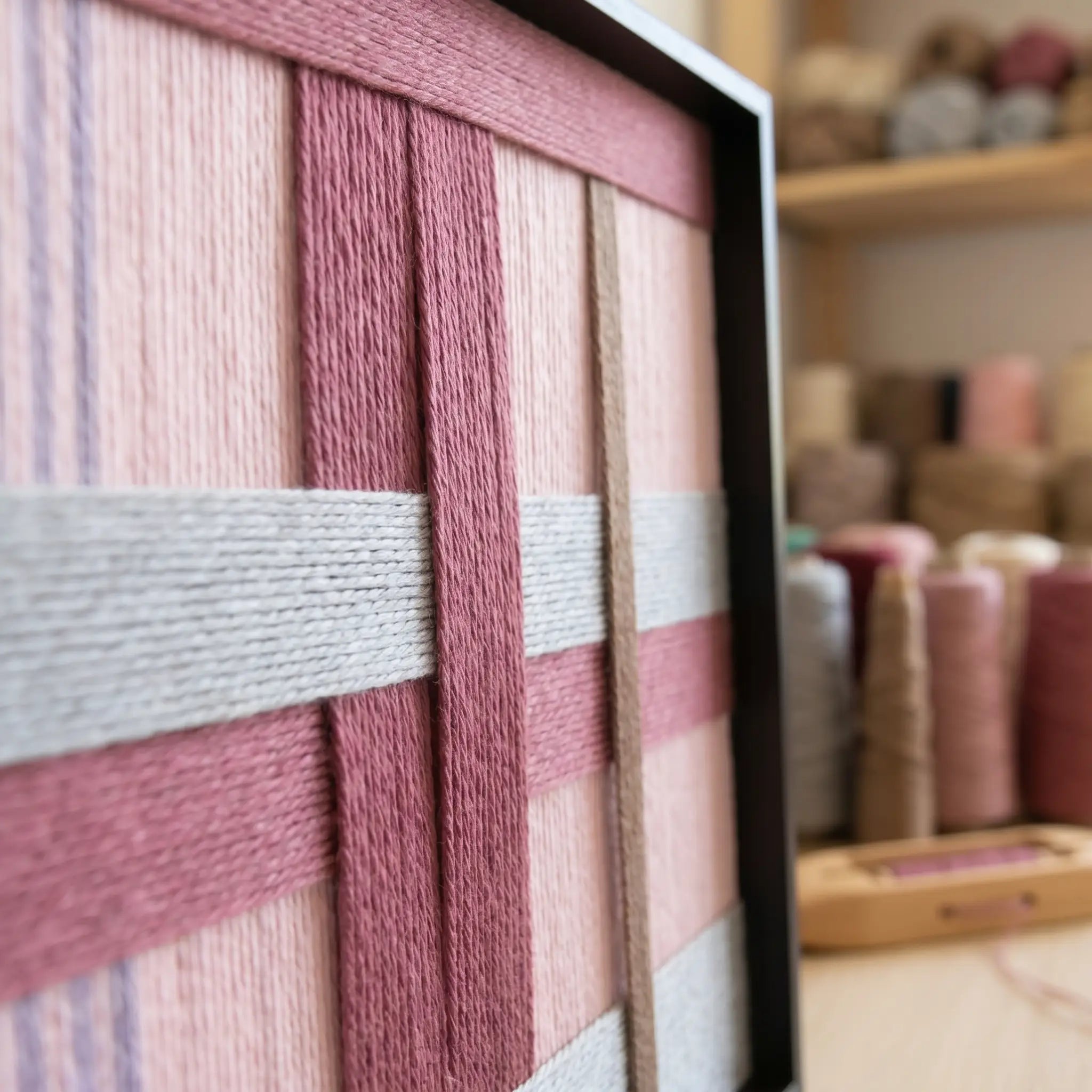 An angled close-up of the "Bloom Forecast" wool art highlighting the intricate hand-wrapped yarn and structural layering technique in a black frame.