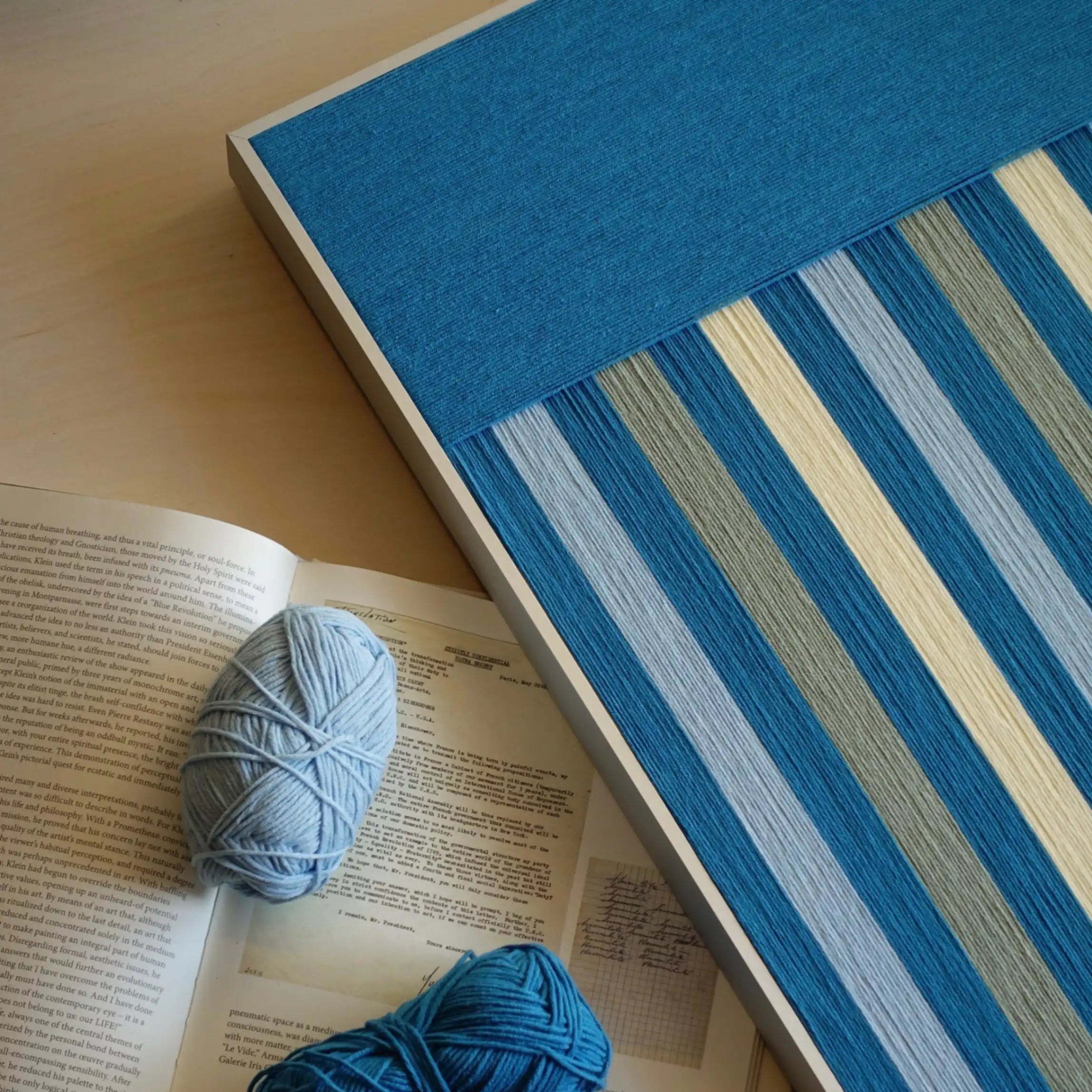 Close-up angled view of Blue Night wool yarn wall art, focusing on tight weave detail and contrast between light and dark blue stripes
