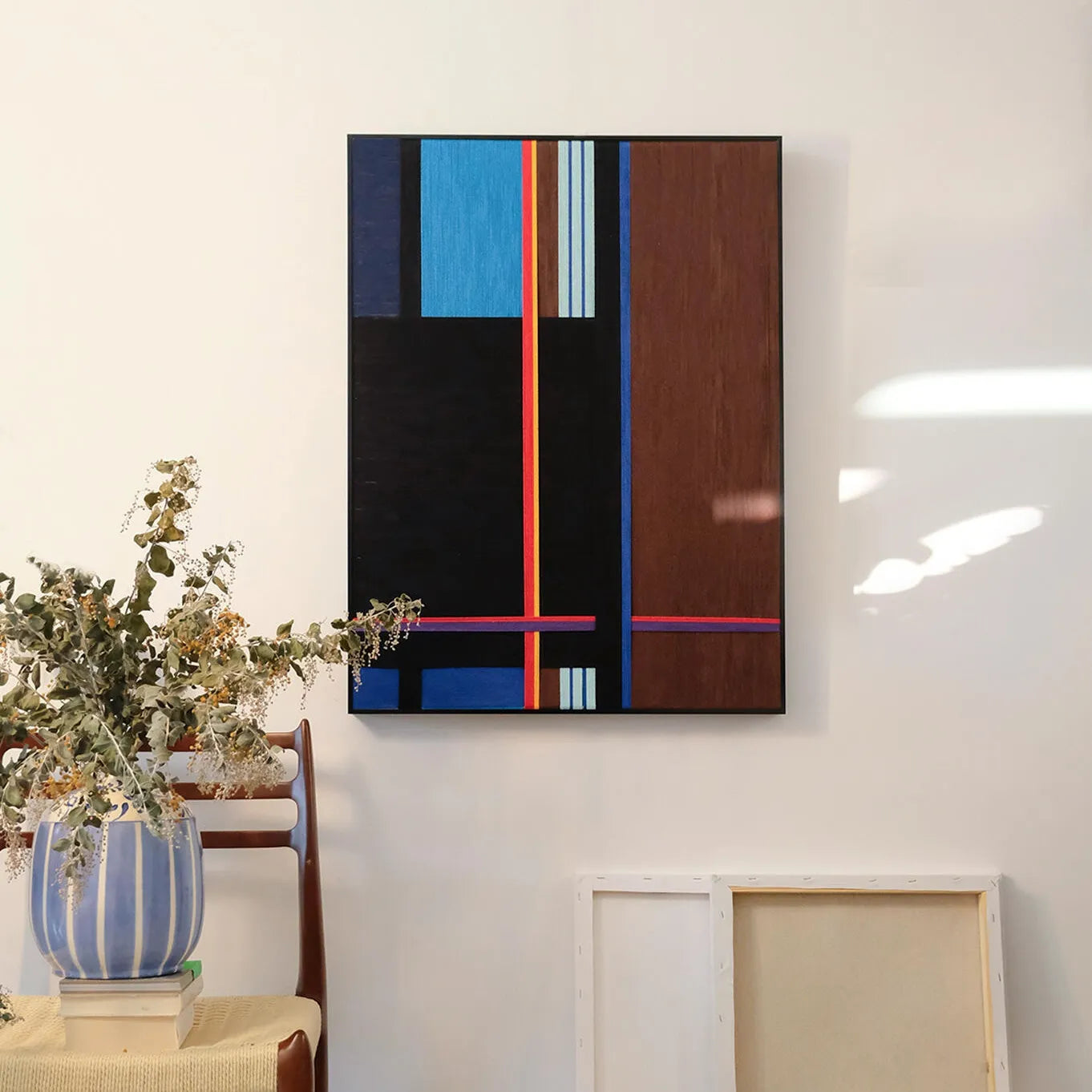 Blue Tide Night Run hand-woven wool yarn wall art featuring bold vertical stripes in ultramarine and sky blue, contrasted by black and dark walnut panels, accented with a slender red stripe, all set in a natural wood frame and displayed above a console table.
