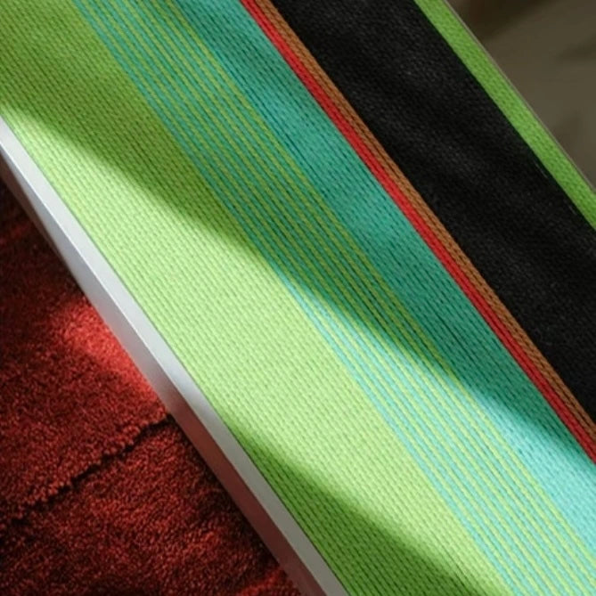 Macro close‑up of Breathing Like Fresh Grass yarn art revealing tight stitch detail and vibrant mint-to-grass-green gradient stripes.
