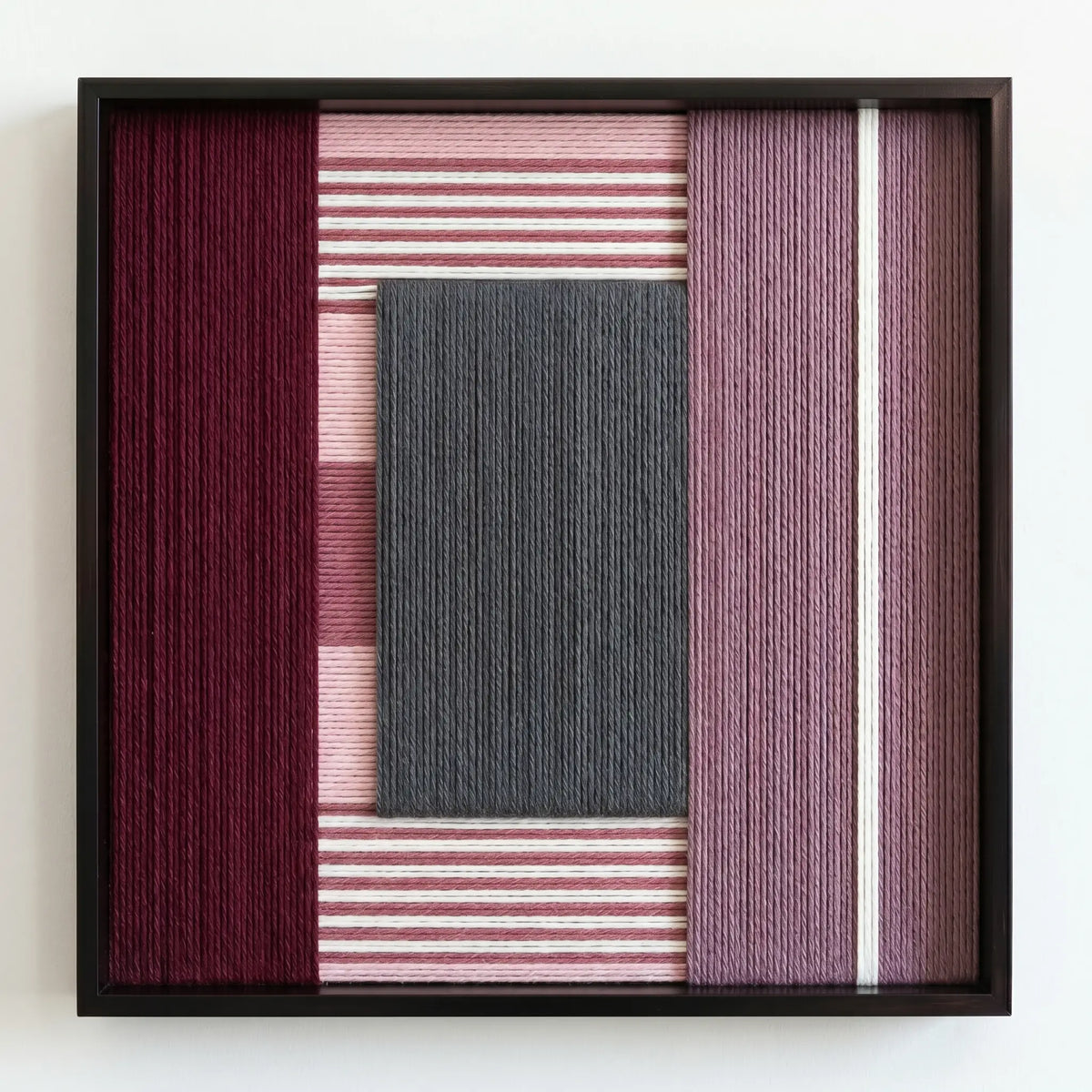 Professional studio shot of the Burgundy Overture hand-woven wool wall art in a square black frame against a clean white background.