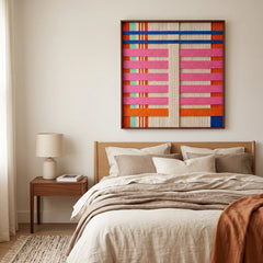 Serene bedroom interior featuring the California Afterglow hand-woven wool tapestry mounted above a wooden bed frame with earth-toned bedding.