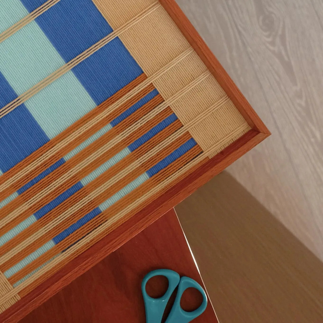 Close-up of Chuan hand-woven yarn art revealing looped wool texture and crisp transitions between sky-blue and beige stripes
