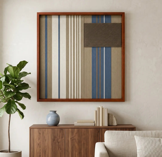 Framed Coastal Diary hand-woven tapestry styled above a dark wooden credenza next to a large indoor potted plant and a light beige sofa in a contemporary living space.
