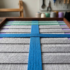 Close-up workshop perspective of the Cobalt Window tapestry showcasing the dimensional depth of the cobalt blue, mint green, and grey hand-wrapped wool yarn.
