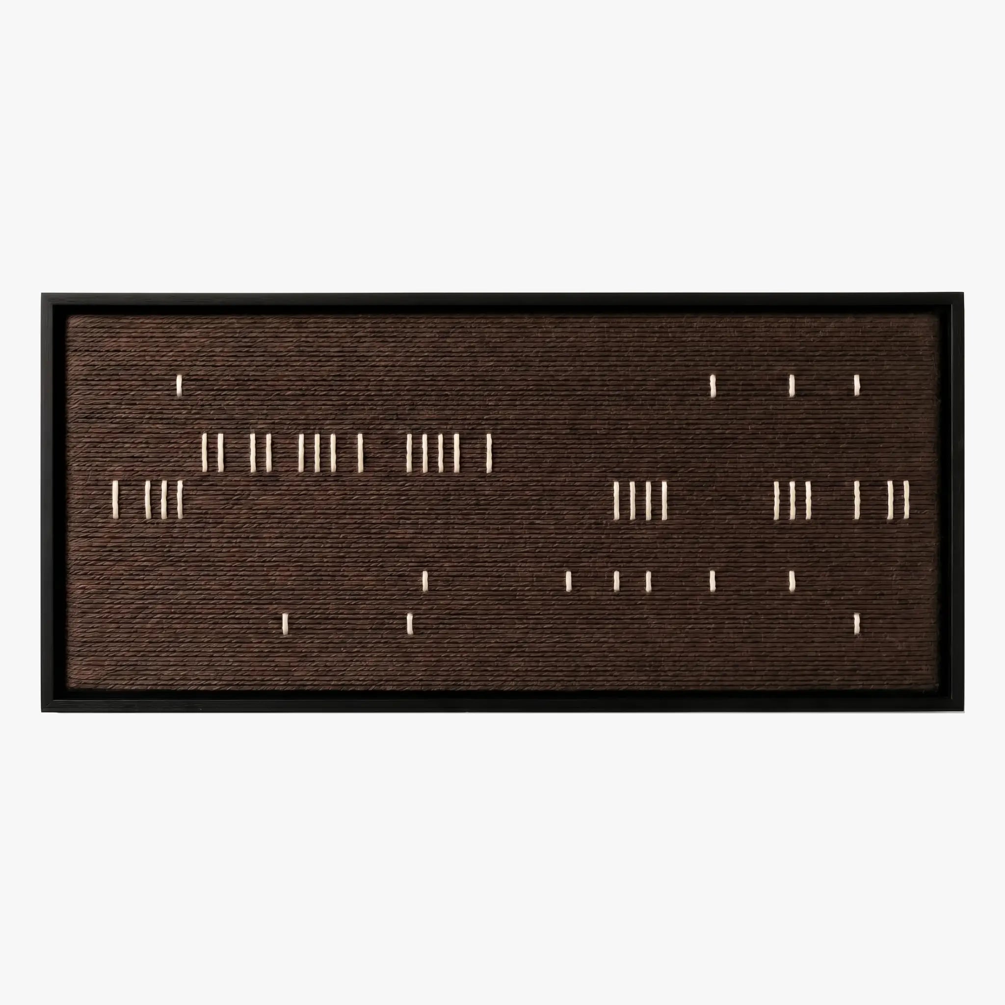 Frontal studio shot of the Cocoa Whispers hand-woven wool wall art featuring scattered white vertical stitches on a dark brown background in a black frame.