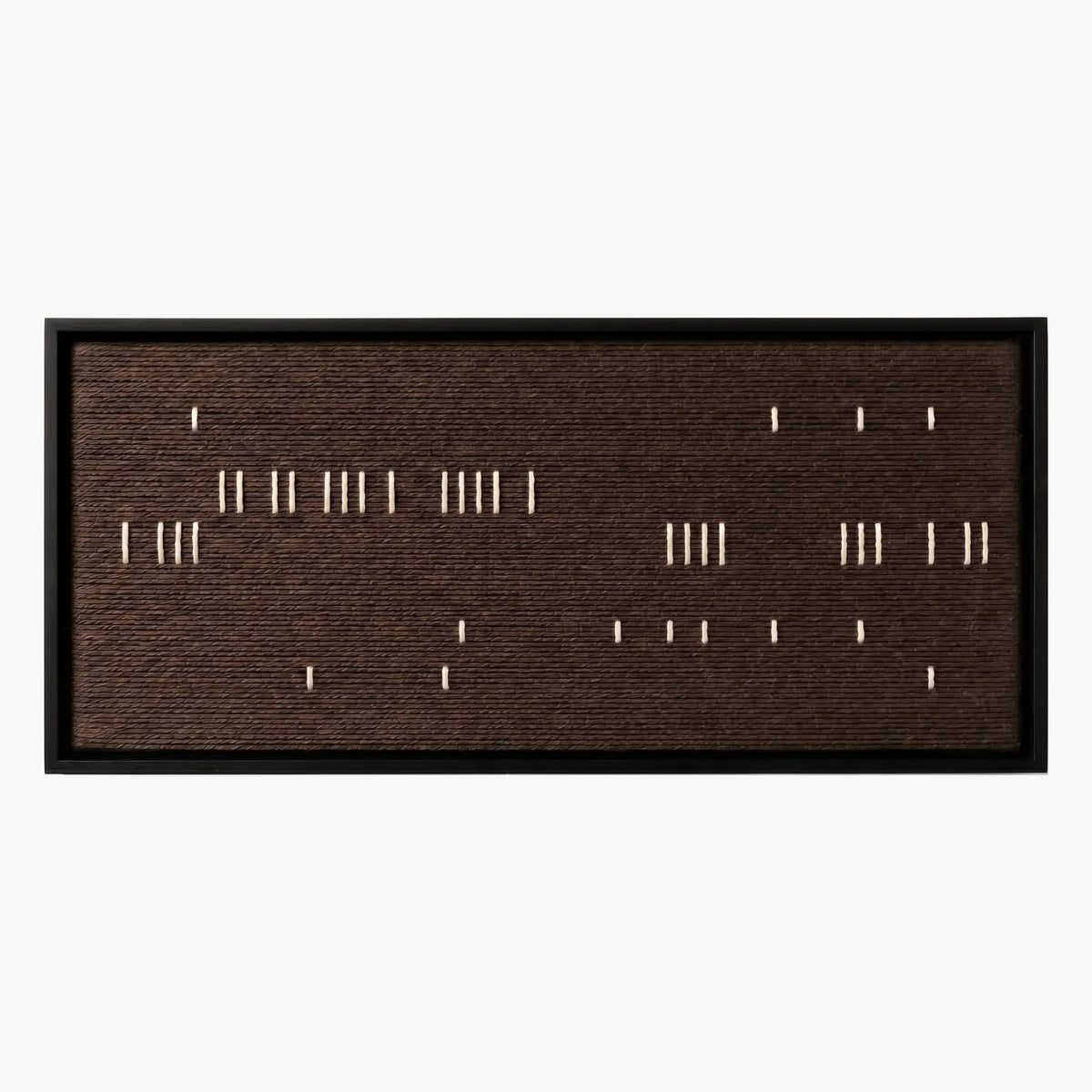 Frontal studio shot of the Cocoa Whispers hand-woven wool wall art featuring scattered white vertical stitches on a dark brown background in a black frame.