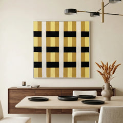 Large square hand-woven wool wall art featuring a bold black, yellow, and cream geometric grid pattern, styled in a minimalist dining room above a walnut sideboard.