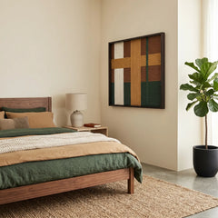 Large square Emerald Fables fiber wall art with forest green, ochre, and brown hand-woven wool patterns hanging in a modern bedroom with a walnut bed frame.