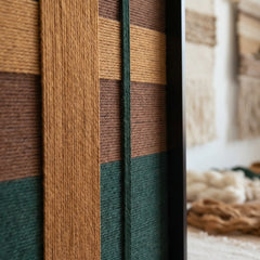 Extreme close-up of the Emerald Fables tapestry showing the high-density forest green and mustard yellow wool yarn textures in a black frame.
