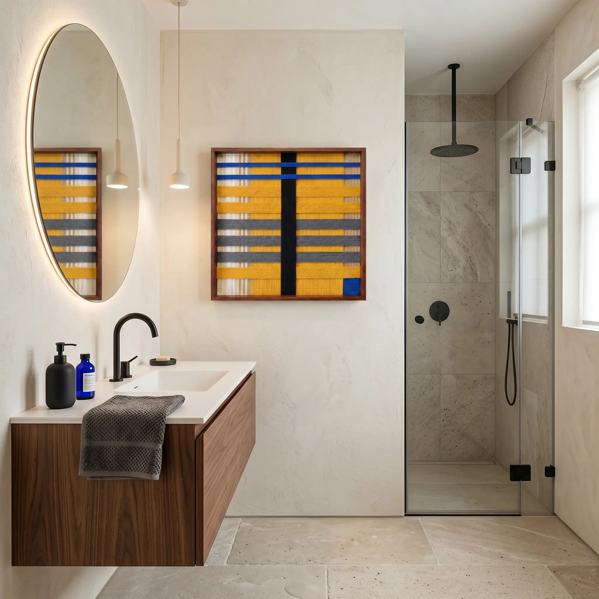 Large square Golden Monsoon fiber wall art featuring vibrant mustard yellow, grey, and blue hand-woven patterns hanging in a modern luxury bathroom with a wooden vanity.