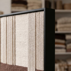 Angled close-up of the framed Ivory Rhythm hand-woven tapestry showcasing the black frame and dimensional cream and brown wool patterns.